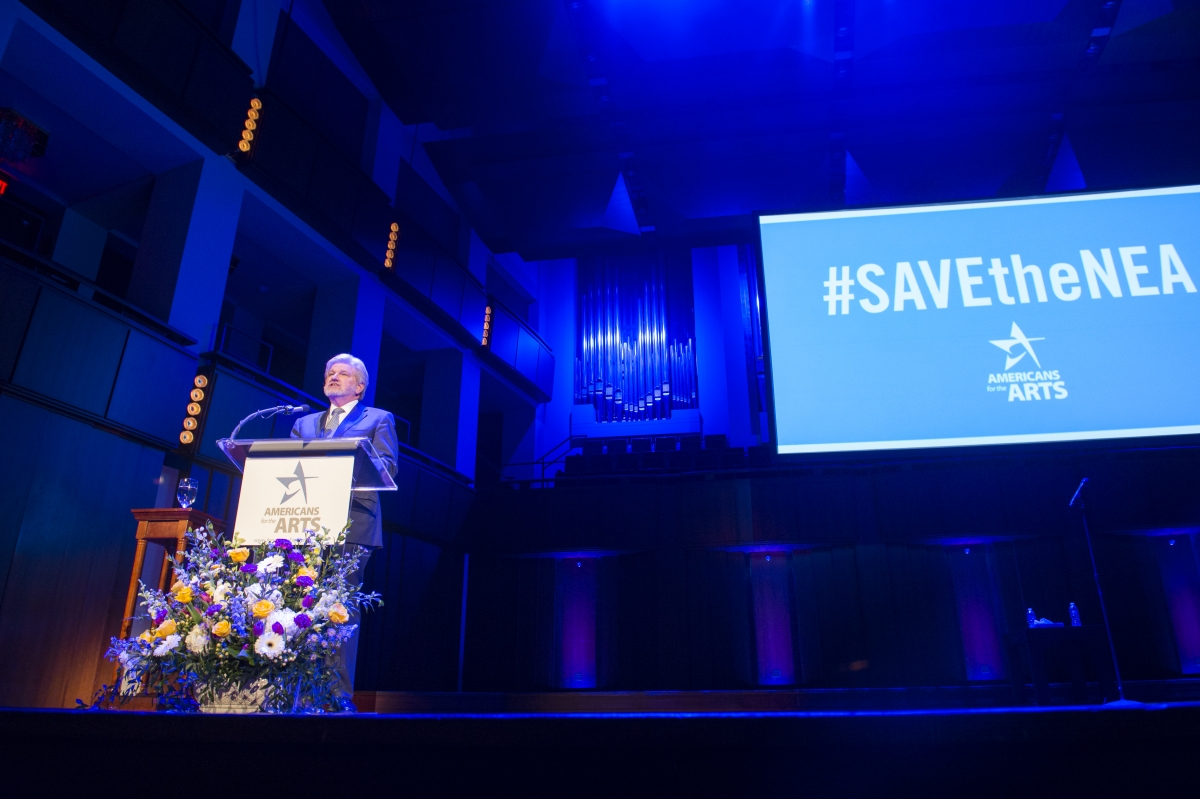 Robert L. Lynch, President & CEO of Americans for the Arts, speaks before the 2017 crowd at the John F. Kennedy Center for the Nancy Hanks Lecture on Arts and Public Policy, including mention of the groundswell #SAVEtheNEA social media campaign. (Photo by Maria Bryk)