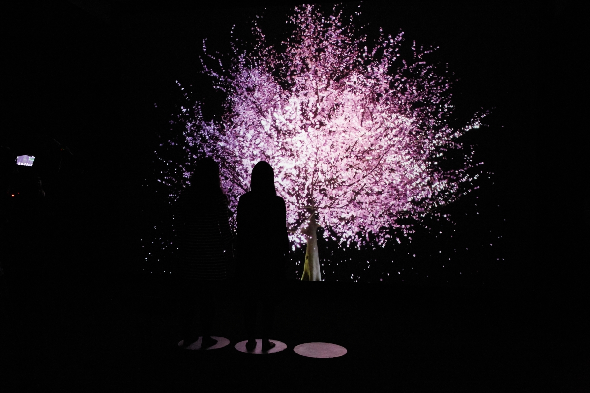 Silhouette of two people facing a lit electronic “tree” by artist Lisa Park at New INC.