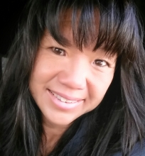 A smiling woman with long dark hair and bangs.