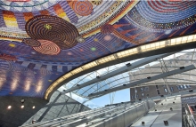Mosaic art on a ceiling above escalators leading into a subway station.