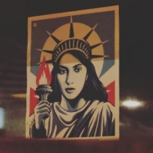 Red, white, and blue illustration of the Statue of Liberty as a real woman holding a torch.